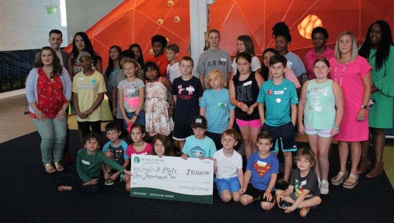 groups of kids standing in front of a $10,000 check